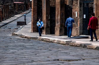 Visitors walk across the archeological site of Pompeii on May 26, 2020, as the country eases its lockdown aimed at curbing the spread of the COVID-19 infection, caused by the novel coronavirus. - Italy's world-famous archeological site Pompeii reopened to the public on May 26,bBut with foreign tourists still prohibited from travel to Italy until June, the site that attracted just under 4 million visitors in 2019 is hoping that for now, Italian tourists can make up at least a fraction of the difference. (Photo by Tiziana FABI / AFP) (Photo by TIZIANA FABI/AFP via Getty Images)