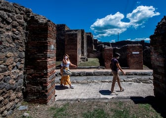 People visit the archeological site of Pompeii on May 26, 2020, as the country eases its lockdown aimed at curbing the spread of the COVID-19 infection, caused by the novel coronavirus. - Italy's world-famous archeological site Pompeii reopened to the public on May 26,bBut with foreign tourists still prohibited from travel to Italy until June, the site that attracted just under 4 million visitors in 2019 is hoping that for now, Italian tourists can make up at least a fraction of the difference. (Photo by Tiziana FABI / AFP) (Photo by TIZIANA FABI/AFP via Getty Images)