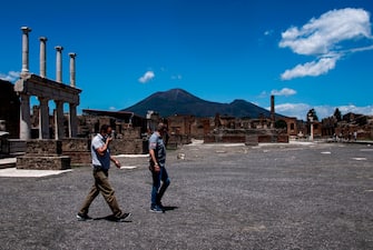 People walks across the archeological site of Pompeii at the bottom of Mount Vesuvius volcano (Rear) on May 26, 2020, as the country eases its lockdown aimed at curbing the spread of the COVID-19 infection, caused by the novel coronavirus. - Italy's world-famous archeological site Pompeii reopened to the public on May 26,bBut with foreign tourists still prohibited from travel to Italy until June, the site that attracted just under 4 million visitors in 2019 is hoping that for now, Italian tourists can make up at least a fraction of the difference. (Photo by Tiziana FABI / AFP) (Photo by TIZIANA FABI/AFP via Getty Images)