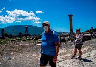 People wearing a face mask visit the archeological site of Pompeii on May 26, 2020, as the country eases its lockdown aimed at curbing the spread of the COVID-19 infection, caused by the novel coronavirus. - Italy's world-famous archeological site Pompeii reopened to the public on May 26,bBut with foreign tourists still prohibited from travel to Italy until June, the site that attracted just under 4 million visitors in 2019 is hoping that for now, Italian tourists can make up at least a fraction of the difference. (Photo by Tiziana FABI / AFP) (Photo by TIZIANA FABI/AFP via Getty Images)