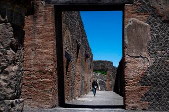 A visitor walks across the archeological site of Pompeii on May 26, 2020, as the country eases its lockdown aimed at curbing the spread of the COVID-19 infection, caused by the novel coronavirus. - Italy's world-famous archeological site Pompeii reopened to the public on May 26,bBut with foreign tourists still prohibited from travel to Italy until June, the site that attracted just under 4 million visitors in 2019 is hoping that for now, Italian tourists can make up at least a fraction of the difference. (Photo by Tiziana FABI / AFP) (Photo by TIZIANA FABI/AFP via Getty Images)