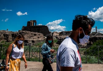 People wearing a face mask visit the archeological site of Pompeii on May 26, 2020, as the country eases its lockdown aimed at curbing the spread of the COVID-19 infection, caused by the novel coronavirus. - Italy's world-famous archeological site Pompeii reopened to the public on May 26,bBut with foreign tourists still prohibited from travel to Italy until June, the site that attracted just under 4 million visitors in 2019 is hoping that for now, Italian tourists can make up at least a fraction of the difference. (Photo by Tiziana FABI / AFP) (Photo by TIZIANA FABI/AFP via Getty Images)
