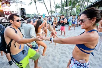 933769406 MIAMI BEACH, FLORIDA - MARCH 17: People dance to DJ music during the launch pool party produced by 93.5FM Revolution Radio Miami at the Nationl Hotel on South Beach as part of Miami Music Week on March 17, 2018 in Miami Beach, Florida. (Photo by Sean Drakes/Getty Images)