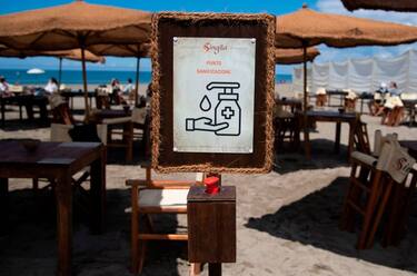 A placard picturing and reading a message to wash your hand with the hydroalcoholic gel on self-service is displayed at the entrance of a beach in Fregene near Rome, on May 30, 2020 as private beaches reopen as Italy eases its lockdown aimed at curbing the spread of the COVID-19 infection, caused by the novel coronavirus. (Photo by Tiziana FABI / AFP) (Photo by TIZIANA FABI/AFP via Getty Images)