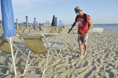 PISA, ITALY - MAY 24:  A lifeguard on the beach wearing a protective mask carries out sanitation and disinfection operations with disinfectant during the Coronavirus pandemic in a bathhouse near Pisa on May 25, 2020 in Pisa, Italy. From 18 May access to the sea is allowed, with strict rules region by region. The bathing establishments have reopened, subject to social distancing measures, after more than two months of a nationwide lockdown and following the anti-contagion rules for Coronavirus with umbrellas spaced about 3 meters apart. There have been over 229,000 reported COVID-19 cases in Italy and more than 32,000 deaths.  (Photo by Laura Lezza/Getty Images)