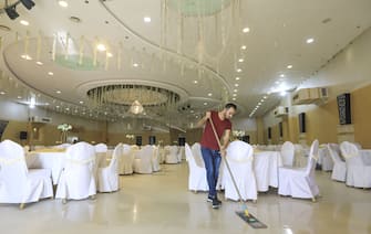 1217458826 A Palestinian worker sweeps a wedding hall in Gaza City on June 3, 2020 following the easing of COVID-19 coronavirus restrictions. (Photo by MAHMUD HAMS / AFP) (Photo by MAHMUD HAMS/AFP via Getty Images)