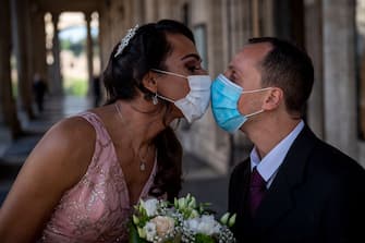 ROME, ITALY - APRIL 24: Sergio and Sophia kiss each other wearing protective masks after their wedding ceremony at Campidoglio, during the Coronavirus (COVID-19) pandemic, on April 24, 2020 in Rome, Italy. Italy is still remaining on lockdown until May 4th to stem the transmission of the Coronavirus (Covid-19). (Photo by Antonio Masiello/Getty Images)