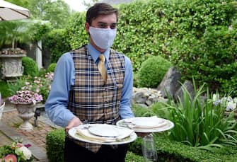 A waiter from The Inn at Little Washington, one of the countrys most renowned restaurants, wears a face mask on the first day of Virginia's phase one reopening in Washington, Virginia on May 29, 2020. - Today marks the beginning of phase one in the state with restaurants reopening following the stay at home orders from the COVID-19 pandemic, provided they can serve customers outdoors with groups sitting at least 6 feet apart. (Photo by Olivier DOULIERY / AFP) (Photo by OLIVIER DOULIERY/AFP via Getty Images)