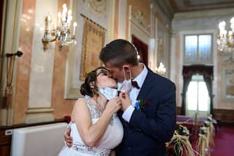 epa08469982 Groom Iker (R) and bride Aranzazu (L) lower their face masks to kiss during their civil wedding at the town hall of Alcala de Henares, Madrid, Spain, 06 June 2020. The nuptial ceremony was one of the first held there since the the state of emergency was implemented in March throughout Spain due to the pandemic COVID-19 disease caused by the SARS-CoV-2 coronavirus. The current regulations for marriages stipulate a maximum number of 10 guests and the mandatory use of protective face masks.  EPA/FERNANDO VILLAR