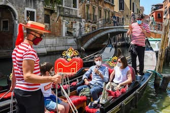 TOPSHOT - Gondoliers go with customers for a gondola ride on a canal in Venice on June 12, 2020 as the country eases its lockdown aimed at curbing the spread of the COVID-19 infection, caused by the novel coronavirus. (Photo by ANDREA PATTARO / AFP) (Photo by ANDREA PATTARO/AFP via Getty Images)
