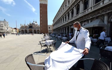 A waiter sets a table on June 12, 2020 at the terrace of the 18th Century Cafe Florian on St. Mark's Square in Venice, which reopens after being closed for three months during the country's lockdown aimed at curbing the spread of the COVID-19 infection, caused by the novel coronavirus. (Photo by ANDREA PATTARO / AFP) (Photo by ANDREA PATTARO/AFP via Getty Images)