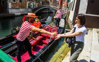 A gondolier (L) sprays sanitizer on a customer's hands prior to going for a gondola ride on a canal in Venice on June 12, 2020 as the country eases its lockdown aimed at curbing the spread of the COVID-19 infection, caused by the novel coronavirus. (Photo by ANDREA PATTARO / AFP) (Photo by ANDREA PATTARO/AFP via Getty Images)