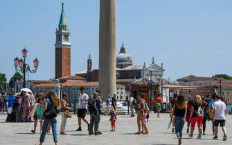 People walk across Piazza Riva degli Schiavoni with San Giorgio Maggiore church in background, on June 12, 2020 in Venice as the country eases its lockdown aimed at curbing the spread of the COVID-19 infection, caused by the novel coronavirus. (Photo by ANDREA PATTARO / AFP) (Photo by ANDREA PATTARO/AFP via Getty Images)