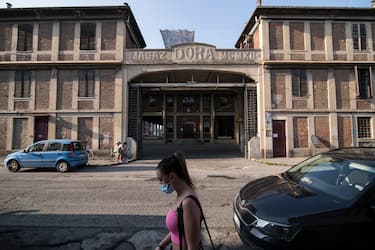 TURIN, ITALY - MAY 21: General view of people with protective mask walk outside the old general warehouse complex Docks Dora of Turin on May 21, 2020 in Turin, Italy. The Docks Dora in Turin are an old general warehouse complex located in the Barriera di Milano district in the northern suburbs of Turin. The mercantile plant, originally a railway exchange between Turin-Milan, had been abandoned in the 1960s and over the decades until the 1990s, the complex was re-used for multiple purposes, such as commercial, tertiary, cultural and entertainment activities. Restaurants, bars, cafes, hairdressers and other shops have reopened, subject to social distancing measures, after more than two months of a nationwide lockdown meant to curb the spread of Covid-19. (Photo by Stefano Guidi/Getty Images)