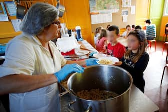 An employee serves lunch to children at the canteen of Courtonne-la-Meurdrac elementary school, which offers organic food exclusively, on September 17, 2018. (Photo by CHARLY TRIBALLEAU / AFP)        (Photo credit should read CHARLY TRIBALLEAU/AFP via Getty Images)