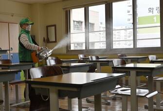 A worker sprays disinfectant in a classroom at a high school in Seoul on May 19, 2020. - South Korea has been held up as a global model in how to curb the coronavirus, but a spike of new cases, driven by a nightclub cluster in Seoul's Itaewon district -- including several gay clubs -- forced authorities to delay last week's planned re-opening of schools for a week. (Photo by Jung Yeon-je / AFP) (Photo by JUNG YEON-JE/AFP via Getty Images)