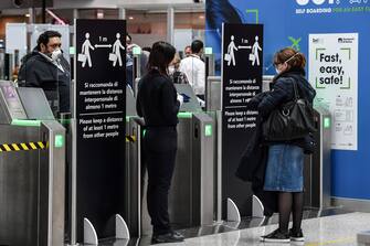 An airport security staff, wearing a respiratory mask (C), controls passengers at Rome's Fiumicino international airport March 13, 2020. - Rome's Ciampino airport will shut to passenger flights from March 13, authorities said, with a Terminal T1 also closing at the city's main Fiumicino facility next week as airlines slash flights to Italy over the coronavirus outbreak. (Photo by Andreas SOLARO / AFP) (Photo by ANDREAS SOLARO/AFP via Getty Images)