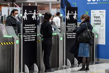 An airport security staff, wearing a respiratory mask (C), controls passengers at Rome's Fiumicino international airport March 13, 2020. - Rome's Ciampino airport will shut to passenger flights from March 13, authorities said, with a Terminal T1 also closing at the city's main Fiumicino facility next week as airlines slash flights to Italy over the coronavirus outbreak. (Photo by Andreas SOLARO / AFP) (Photo by ANDREAS SOLARO/AFP via Getty Images)