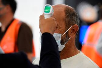 A stewardess checks the temperature of a passenger on the day of the re-opening of Paris' Orly airport on June 26, 2020. (Photo by ERIC PIERMONT / AFP) (Photo by ERIC PIERMONT/AFP via Getty Images)