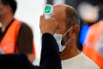1222962033 A stewardess checks the temperature of a passenger on the day of the re-opening of Paris' Orly airport on June 26, 2020. (Photo by ERIC PIERMONT / AFP) (Photo by ERIC PIERMONT/AFP via Getty Images)