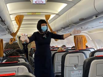 MILAN, ITALY - JUNE 03:  Flight hostess wearing PPE gives directions to passengers on the plane on the first day of reopening of Malpensa Airport after the lockdown on June 03, 2020 in Milan, Italy. Flights have started again from the ease of the Covid-19 lockdown on June 3rd.  (Photo by Lorenzo Palizzolo/Getty Images)