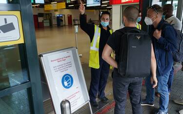 BERLIN, GERMANY - JUNE 19: An airport worker wearing a protective face mask, who said she did not mind being photographed, directs tarvellers at Tegel Airport during the novel coronavirus pandemic on June 19, 2020 in Berlin, Germany. While travel restrictions put in place across the European Union in March to stem the spread of the virus have recently been mostly lifted ahead of the economically crucial summer tourist season, travel is picking up only slowly and the number of flights on offer remains low for many destinations.  (Photo by Sean Gallup/Getty Images)