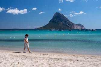 OLBIA, ITALY - JUNE 14: A lady walks on a beach in Sardinia and wears the protective mask imposed for the spread of Covid-19 on June 14, 2020 in Olbia, Italy. The whole country is returning to normality after more than two months of a nationwide lockdown meant to curb the spread of Covid-19. (Photo by Emanuele Perrone/Getty Images)
