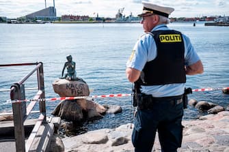 1224453038 A policeman stands on July 3, 2020 in front of the "Little Mermaid" sculpture after it has been vandalised in Copenhagen. (Photo by Niels Christian Vilmann / Ritzau Scanpix / AFP) / Denmark OUT (Photo by NIELS CHRISTIAN VILMANN/Ritzau Scanpix/AFP via Getty Images)