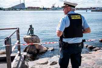 A policeman stands on July 3, 2020 in front of the "Little Mermaid" sculpture after it has been vandalised in Copenhagen. (Photo by Niels Christian Vilmann / Ritzau Scanpix / AFP) / Denmark OUT (Photo by NIELS CHRISTIAN VILMANN/Ritzau Scanpix/AFP via Getty Images)