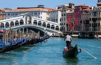A gondolier goes with customers for a gondola ride on the Grand Canal near Rialto Bridge in Venice on June 12, 2020 as the country eases its lockdown aimed at curbing the spread of the COVID-19 infection, caused by the novel coronavirus. (Photo by ANDREA PATTARO / AFP) (Photo by ANDREA PATTARO/AFP via Getty Images)