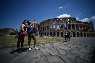 Visitors stand by the Colosseum monument which reopens to the public on June 1, 2020 in Rome, while the country eases its lockdown aimed at curbing the spread of the COVID-19 infection, caused by the novel coronavirus. - The Colosseum monument reopens on June 1, 2020 after having been closed since March 8, 2020, with adequate sanitary protection for staff and visitors, secure routes, compulsory reservations and modified schedules to avoid crowds at peak times. (Photo by Filippo MONTEFORTE / AFP) (Photo by FILIPPO MONTEFORTE/AFP via Getty Images)
