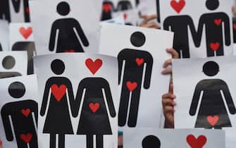 People hold placards depicting hearts and couples, during a flash mob for the annual Lesbian, Gay, Bisexual and Transgender (LGBT) Pride Parade in Milan, on June 25, 2016.  / AFP / GIUSEPPE CACACE        (Photo credit should read GIUSEPPE CACACE/AFP via Getty Images)