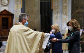 ROME, ITALY - MAY 18: The parish priest Marco Gnavi of Santa Maria in Trastevere, of the Community of Sant'Egidio administers the sacrament of Communion while celebrating Mass, after more than two months of lockdown in which religious services were not celebrated on May 18, 2020 in Rome, Italy. Museums, restaurants, bars, cafes, hairdressers and other shops have reopened, subject to social distancing measures, after more than two months of a nationwide lockdown meant to curb the spread of Covid-19. Churches are starting to celebrate Mass again, but there will be strict social distancing and worshippers must wear face masks. (Photo by Marco Di Lauro/Getty Images)