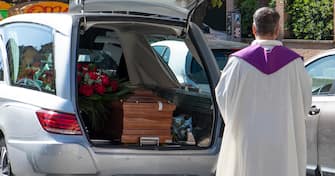 Un prete benedice una salma, situata allÕinterno del carro funebre, fuori della sua chiesa durante lÕemergenza coronavirus a Roma, 27 aprile 2020.
MAURIZIO BRAMBATTI/ANSA