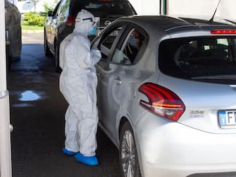 MILAN, ITALY - JUNE 05: A nurse, wearing a protective suit, offers a mouth and nose swab through a car window at a 'drive-through' coronavirus testing facility at Ospedale San Raffaele Milan, Italy. Many Italian businesses have been allowed to reopen, after more than two months of a nationwide lockdown meant to curb the spread of Covid-19.  (Photo by Pietro D'Aprano/Getty Images)