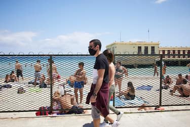 PALERMO, ITALY - JUNE 07:  A man and woman wearing protective mask walks on Mondello beach on the first day of the reopening of the bathing facilities on June 07, 2020 in Palermo, Italy. Many Italian businesses have been allowed to reopen, after more than two months of a nationwide lockdown meant to curb the spread of Covid-19. (Photo by Lorenzo Palizzolo/Getty Images)