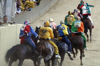 The horses from various districts race at the second turn of the Palio of Siena horse race, held to celebrate the apparition of the Assunta virgin, on August 16, 2008 in Siena. Giuseppe Zedde on Elisir Loguduro of the district of Caterpillar won the event. AFP PHOTO / NICO CASAMASSIMA (Photo credit should read NICO CASAMASSIMA/AFP via Getty Images)