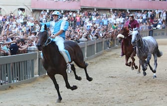 SIENA, ITALY - AUGUST 16: (RESTRICTED TO EDITORIAL USE - NO MARKETING, NO ADVERTISING CAMPAIGNS)  Giovanni Atzeni (L), known as Tittia, rides his horse bareback on his way to winning the Palio dell'Assunta horse-race at Piazza del Campo square on August 16, 2013 in Siena, Italy. The Palio races in Siena, in which riders representing city districts compete, and takes place twice a year in the summer in a tradition that dates back to 1656. (Photo by Chris Jablinski/Getty Images)