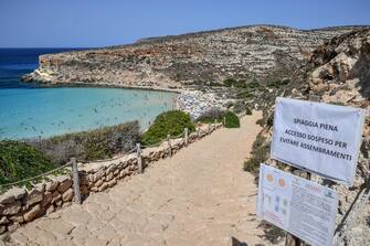 Un cartello con le regole per il distanziamento sociale a causa del Covid-19 sul sentiero che porta alla spiaggia e all'isola dei Conigli, isola di Lampedusa, 5 agosto 2020.
ANSA/ALESSANDRO DI MEO