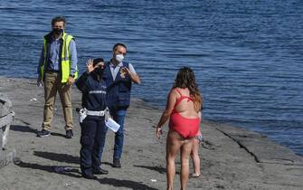 Local police officers wearing protective masks  impose a fine to a woman who was with his daughter on a beach on the waterfront. Italy begins a staged end to a nationwide lockdown due to the spread of the coronavirus disease, but sea baths iare still prohibited. (Salvatore Laporta / IPA/Fotogramma,  - 2020-05-09) p.s. la foto e' utilizzabile nel rispetto del contesto in cui e' stata scattata, e senza intento diffamatorio del decoro delle persone rappresentate