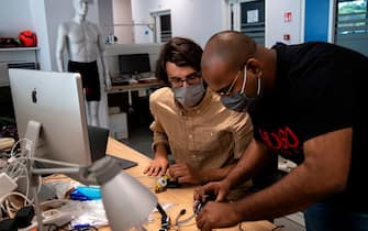 A photo taken on May 21, 2020 shows engineers, wearing a face mask, working on prototypes of a smart device called "iFeel-You", a bracelet used to maintain safe distance between people in daily life situations as well as on the beach, at the Italian Institute of Technology ((IIT)) in Genoa, Liguria, as the country eases its lockdown during the Phase 2 of deconfinment within the COVID-19 infection, caused by the novel coronavirus. - ITT is aiming to find a company able to produce the bracelet on an industrial scale at low price in a short time. (Photo by MARCO BERTORELLO / AFP) (Photo by MARCO BERTORELLO/AFP via Getty Images)