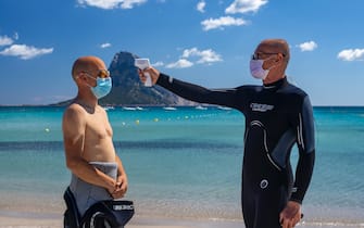 1249795715 OLBIA, ITALY - JUNE 14: body temperature measurement before scuba diving and use of the projection mask. The manager of the diving center respects the rules imposed against the spread of Covid-19 on June 14, 2020 in Olbia, Italy. The whole country is returning to normality after more than two months of a nationwide lockdown meant to curb the spread of Covid-19. (Photo by Emanuele Perrone/Getty Images)