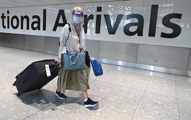 Passengers wearing a face mask or covering due to the COVID-19 pandemic, arrive at Heathrow airport, west London, on July 10, 2020. - The British government on Friday revealed the first exemptions from its coronavirus quarantine, with arrivals from Germany, France, Spain and Italy no longer required to self-isolate from July 10. Since June 8, it has required all overseas arrivals -- including UK residents -- to self-quarantine to avoid the risk of importing new cases from abroad. (Photo by DANIEL LEAL-OLIVAS / AFP) (Photo by DANIEL LEAL-OLIVAS/AFP via Getty Images)