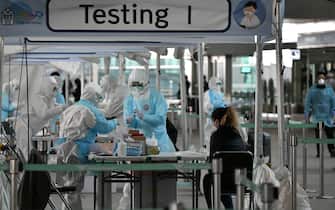 TOPSHOT - Medical staff wearing protective clothing take test samples for the COVID-19 coronavirus from a foreign passenger at a virus testing booth outside Incheon international airport, west of Seoul, on April 1, 2020. - The first charter flight arranged by South Korean government to evacuate its citizens from coronavirus-hit Italy returned home with 309 citizens on April 1, amid the worsening virus outbreak in the European country. (Photo by Jung Yeon-je / AFP) (Photo by JUNG YEON-JE/AFP via Getty Images)