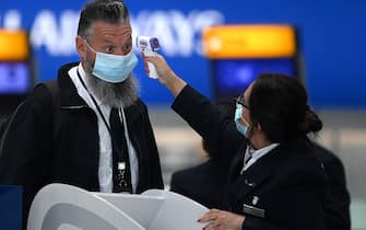 Passengers wearing face masks or covering due to the COVID-19 pandemic, have their temperature taken as they queue at a British Airways check-in desk at Heathrow airport, west London, on July 10, 2020. - The British government on Friday revealed the first exemptions from its coronavirus quarantine, with arrivals from Germany, France, Spain and Italy no longer required to self-isolate from July 10. Since June 8, it has required all overseas arrivals -- including UK residents -- to self-quarantine to avoid the risk of importing new cases from abroad. (Photo by DANIEL LEAL-OLIVAS / AFP) (Photo by DANIEL LEAL-OLIVAS/AFP via Getty Images)