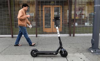 A man walks past a Bird scooter on a Los Angeles sidewalk on March 19, 2020. - Electric scooter companies Bird and Lime have suspended services across North America for an indefinite period amid the coronavirus epidemic and a drop in user numbers. (Photo by Frederic J. BROWN / AFP) (Photo by FREDERIC J. BROWN/AFP via Getty Images)