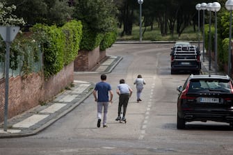 MAJADAHONDA, MADRID, SPAIN - APRIL 26. A man watches with two sons ride their scooters near their homeâ   on April 26, 2020, in Majadahonda, Madrid, Spain. Children in Spain, which has had one of the stricter lockdowns in Europe, are now allowed to leave their homes for up to an hour per day. The country has had more than 220,000 confirmed cases of COVID-19 and over 20,000 reported deaths, although the rate has declined after weeks of quarantine measures. (Photo by Miguel Pereira/Getty Images)