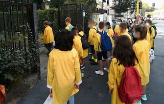 1228509594 MILAN, ITALY - SEPTEMBER 14: Students wearing protective masks and keeping their social distance arrive at elementary school , on September 14, 2020 in Milan, Italy. Today for millions of Italian students is the first day of the school with new rules for COVID-19 like social distance, protective masks and outdoor classess. (Photo by Pier Marco Tacca/Getty Images)