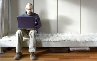 Man on Laptop in Lounge Room. (Photo by Brenda Liu/Construction Photography/Avalon/Getty Images)