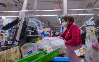 1208283600 A cashier wearing a face masks processes a customer's payment at a supermarket on March 26, 2020 in the Portuense district of Rome during the country's lockdown following the COVID-19 new coronavirus pandemic. (Photo by ANDREAS SOLARO / AFP) (Photo by ANDREAS SOLARO/AFP via Getty Images)